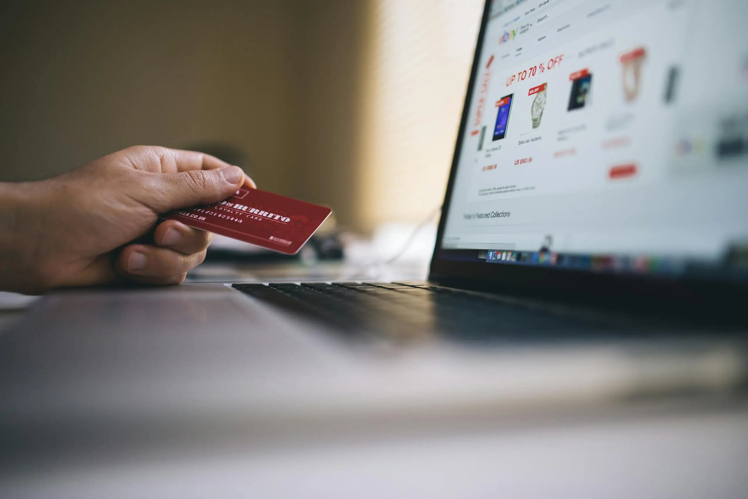 person holding a credit card while shopping online on a laptop indicating ecommerce transactions. 34577 scaled Person holding a credit card while shopping online on a laptop, indicating ecommerce transactions.