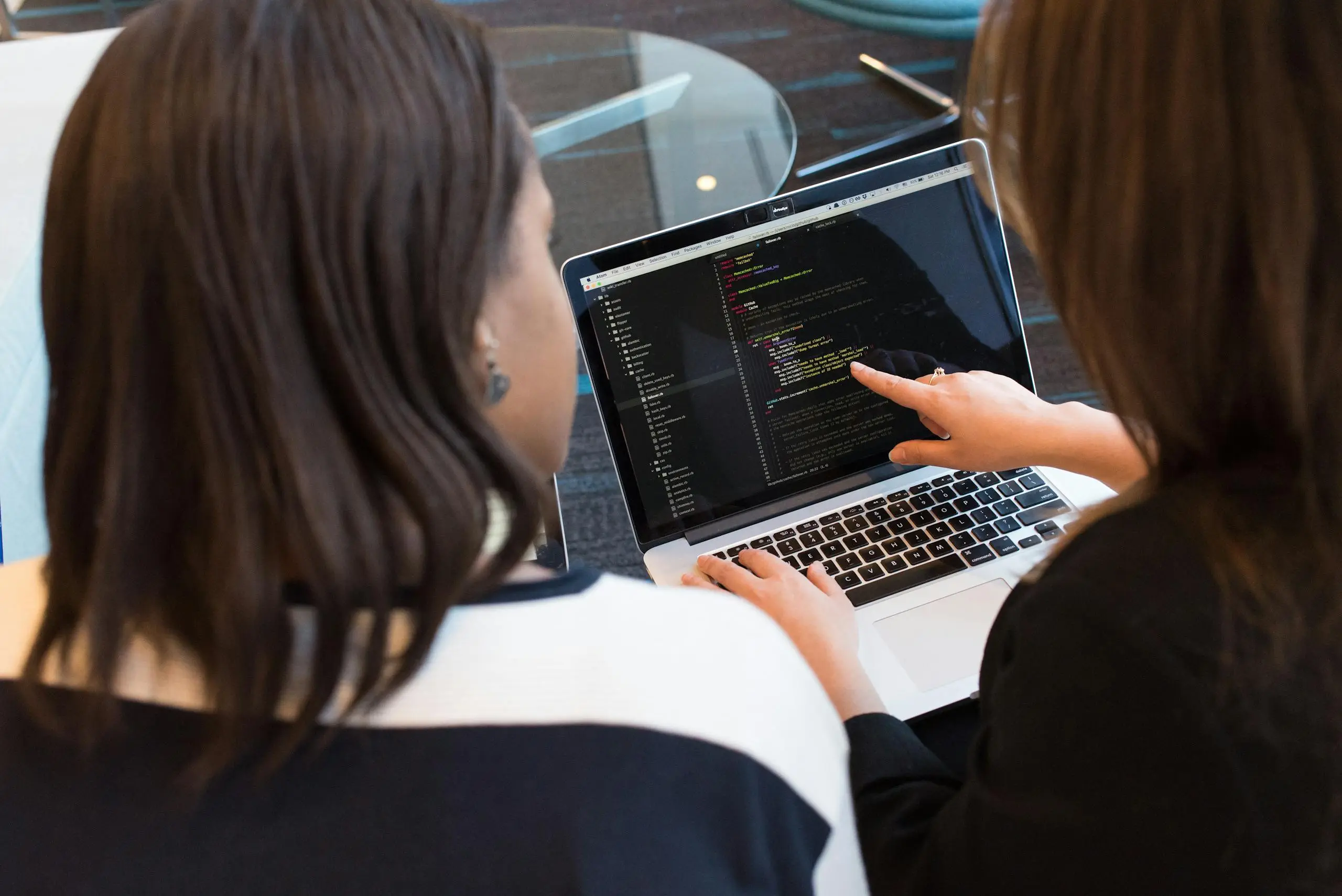 two women working together on software programming indoors focusing on code. 1181263 scaled Two women working together on software programming indoors, focusing on code.